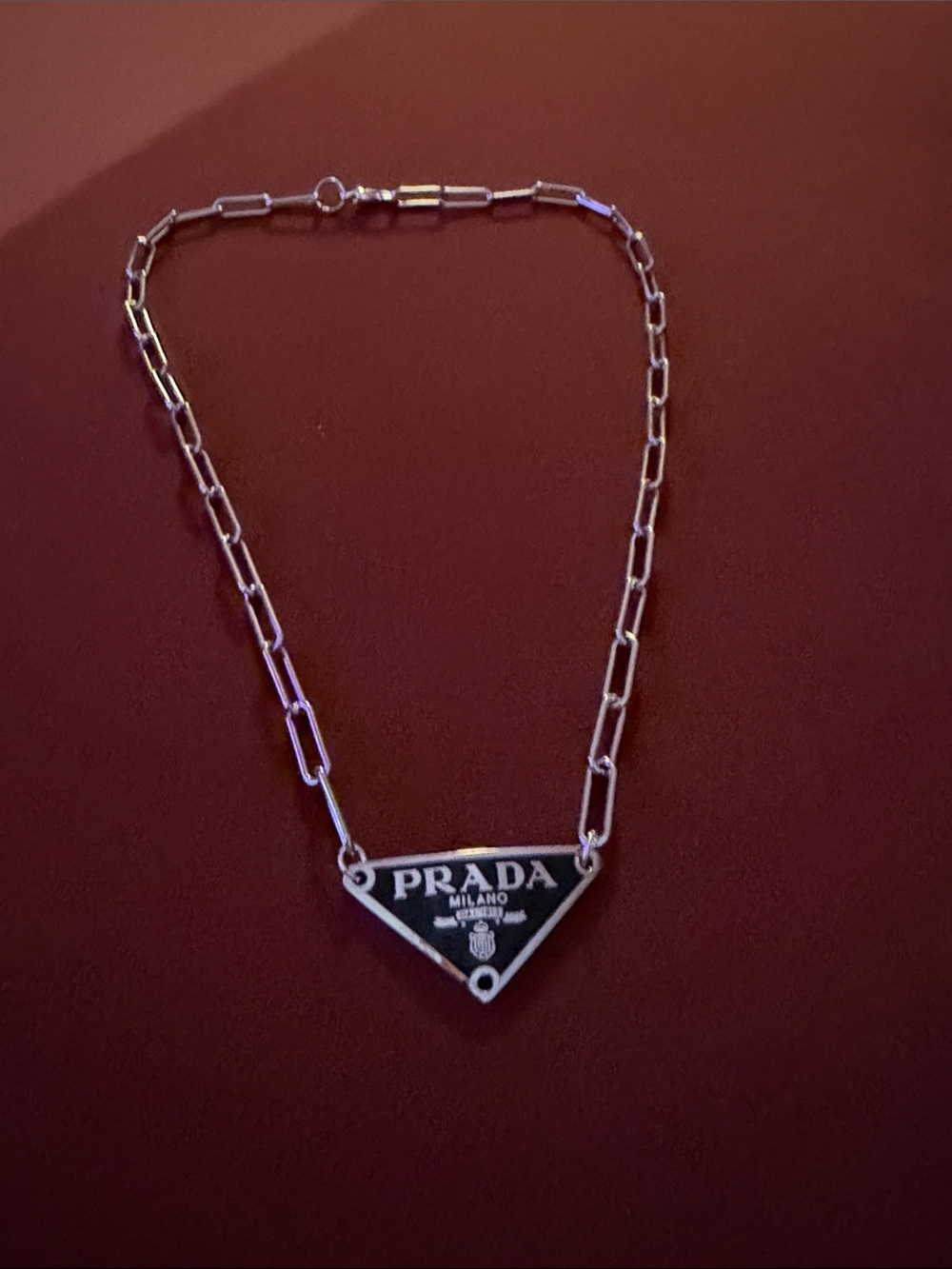 An Adjustable Silver Chain Necklace with Black Triangle Logo Pendant